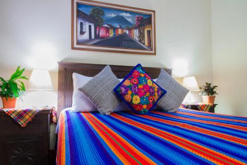 ein Bett mit bunten Decken und Kissen darauf in der Unterkunft Hostal Antigua in Antigua Guatemala