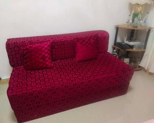 um sofá vermelho com almofadas cor-de-rosa num quarto em Affordable Spacious Bedroom & Bathroom near DVO Airport em Davao