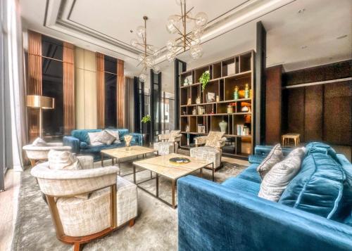 - un salon avec un canapé bleu et des chaises dans l'établissement Grand Sungkono Lagoon Apartment 2BR Surabaya by Le Ciel Hospitality, à Surabaya