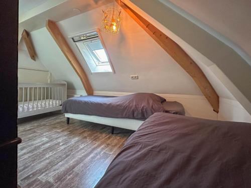 een slaapkamer op zolder met 2 bedden en een raam bij Uilennest in Haaren