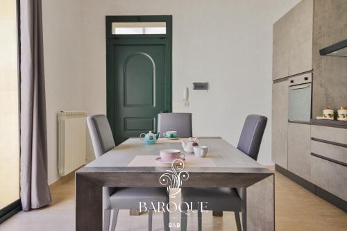 a kitchen with a table with chairs and a green door at Baroque B&B in Lecce