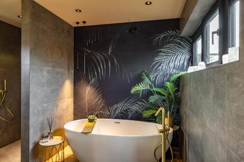 a bathroom with a bath tub and plants on the wall at Landgoed Schoolland in Garrelsweer