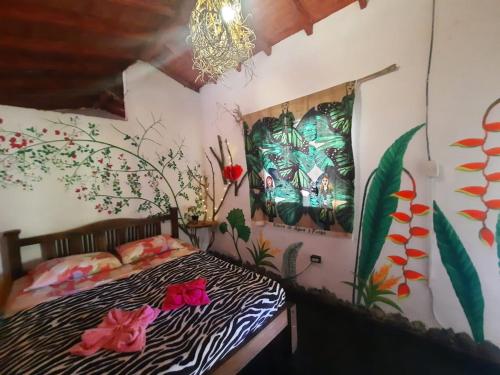 1 dormitorio con cama con estampado de cebra y pinturas en la pared en Eco Hostal Tierra de Agua y Fuego, en San Rafael