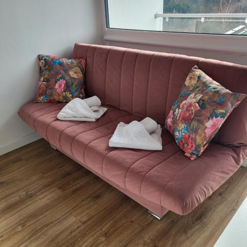 a red couch with two pillows and towels on it at Apartamenty Ustroń Wczasowa 90 in Ustroń