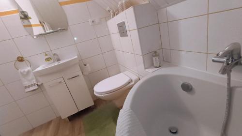 a white bathroom with a toilet and a bath tub at Rodinný Penzion Karin in Ostrava