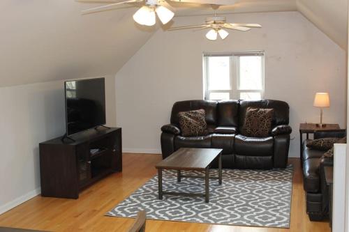 a living room with a leather couch and a tv at Lincoln Park Living - 3 Queen Beds - Sleeps 6 in Chicago