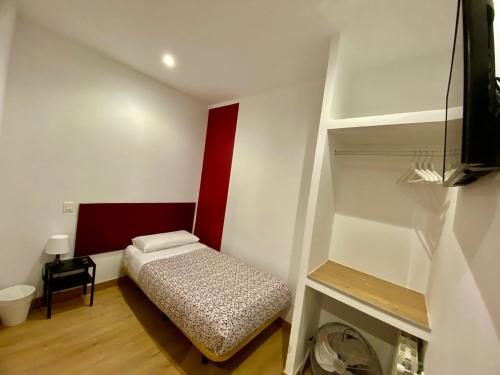 Habitación pequeña con cama y estante en Hostal La Casa de La Plaza, en Madrid