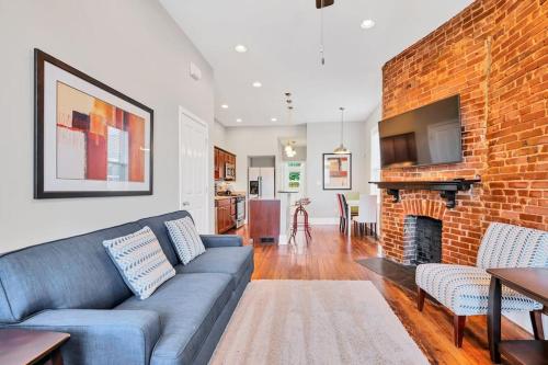 a living room with a couch and a brick wall at St Louis Townhome-Perfect for Groups in Tower Grove