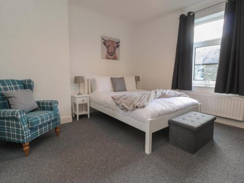 a bedroom with a bed and a chair and a window at 10 Haw Grove in Skipton