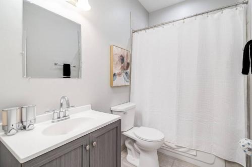 a white bathroom with a sink and a toilet at Suite 1 on Southport 4 Queen Beds in Chicago