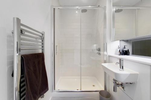 Stay in Style: Modern 2-Bed In Trendy London Area في لندن: حمام أبيض مع دش ومغسلة