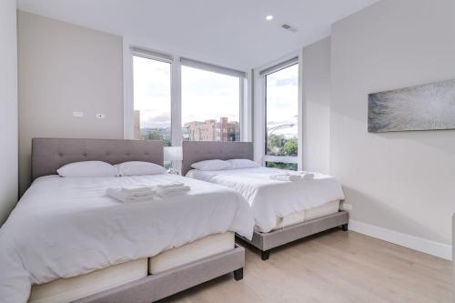 two beds in a white room with windows at Stunning Condo #2 - Downtown River North in Chicago