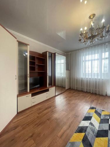 duży salon z drewnianą podłogą i żyrandolem w obiekcie 1 комнатная Таттимбета 5 (Юго-Восток) w mieście Karaganda