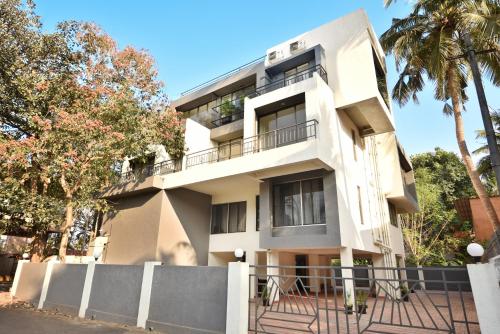 a white building with trees in front of it at Lembranca Studios & Suites Near Famous FLOATING CASINOS of Goa in Porvorim