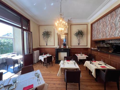 a restaurant with tables and chairs and a chandelier at Hotel Canteklaar in De Haan
