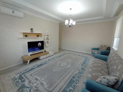 uma sala de estar com um sofá e uma televisão em Уютная квартира с видом на горы em Shymkent