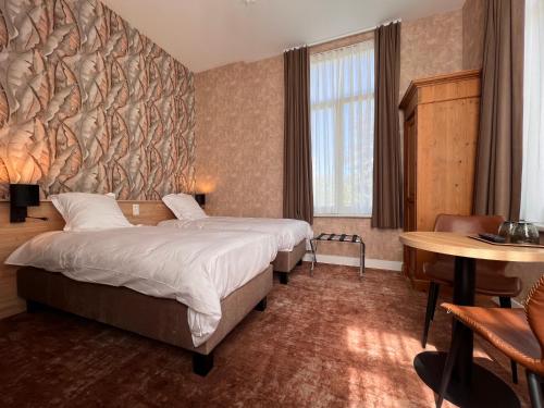 デ・ハーンにあるHotel Canteklaarのベッド2台とテーブルが備わるホテルルームです。