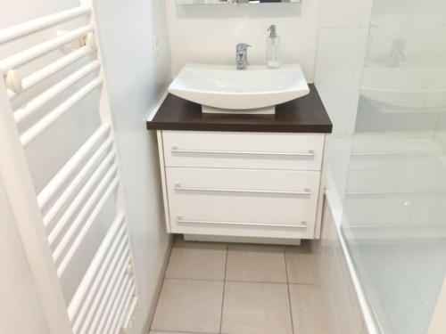a white bathroom with a sink and a walk in shower at Arcachon Hyper Centre - spacieux appartement 2 chambres parking et terrasse in Arcachon
