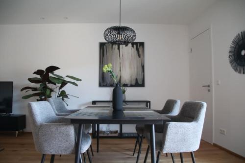 a dining room table with chairs and a vase on it at Modernes City-Apartment in Neustadt an der Weinstraße