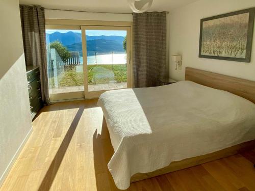 a bedroom with a large bed and a large window at EnjoyIseoLake - Corinto - wonderful Lake front apartment in Parzanica