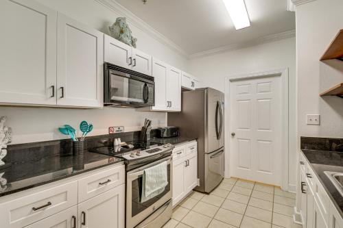 a kitchen with white cabinets and stainless steel appliances at Foley Condo with Pool Access 10 Mi to Gulf Shores! in Foley