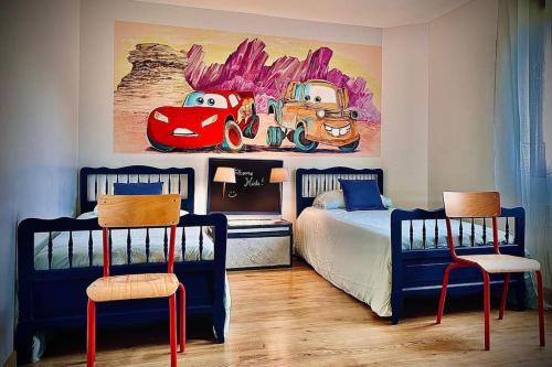 - une chambre avec 2 lits et une peinture d'une voiture de course dans l'établissement Le Family Cottage du Brask, à La Motte-du-Caire