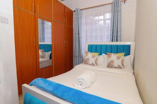 een slaapkamer met een bed met een blauw hoofdeinde bij FOREVER 3 RESIDENCE in Naivasha