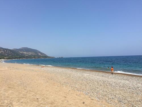 a person walking on a beach near the ocean at Villa Pergia Latchi in Polis Chrysochous