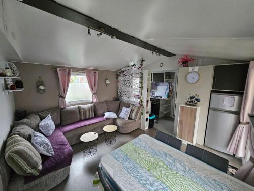 sala de estar con sofá púrpura y cocina en Assist' Mobil Home 77 - Mobil home 3 chambres 2 salles de bain au calme en Onzain