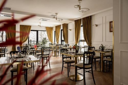 a dining room with tables and chairs and windows at Aparthotel Renesans Zakopane in Zakopane