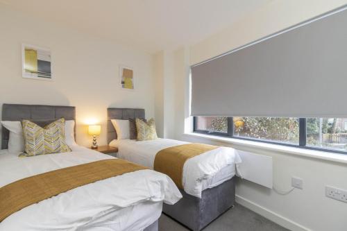 2 camas en una habitación blanca con ventana en OPP Exeter LH11 - Behind the Cathedral with free parking! BIG SAVINGS booking 7 nights or more!, en Exeter