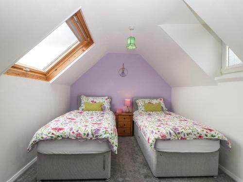 a attic bedroom with two beds and a window at Platform 13 Railway Cottage in Llandudno Junction