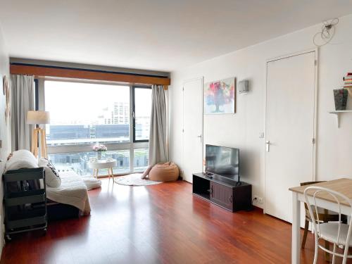 un salon avec une télévision et une grande fenêtre dans l'établissement Sur les hauteurs de Montparnasse, à Paris