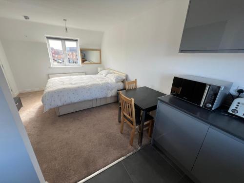 a bedroom with a bed and a desk with a microwave at Apartment suites in Broughton, Milton keynes in Broughton
