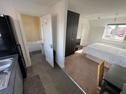 ein kleines Schlafzimmer mit einem Bett und einem Badezimmer in der Unterkunft Apartment suites in Broughton, Milton keynes in Broughton