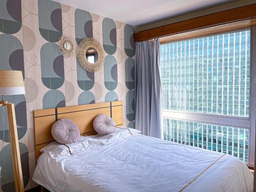 une chambre avec un lit et une grande fenêtre dans l'établissement Sur les hauteurs de Montparnasse, à Paris