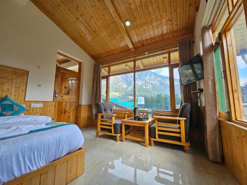 a bedroom with a bed and a table and chairs at Purnima Guest House in Manāli