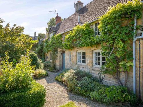 an old stone house with ivy growing on it at Hope Cottage in Moreton in Marsh