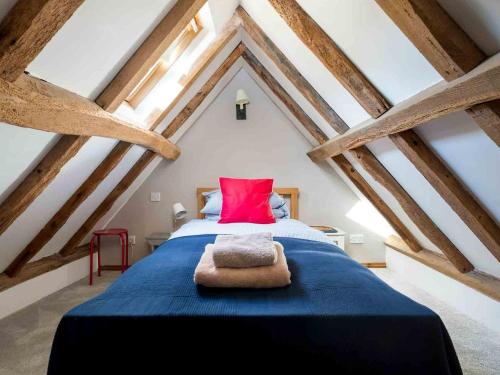 a bedroom with a blue bed with a red pillow at Hope Cottage in Moreton in Marsh