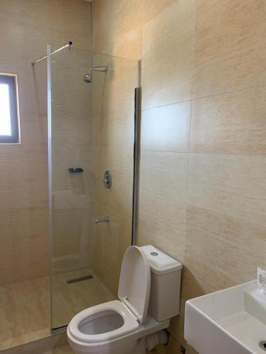 a bathroom with a shower and a toilet and a sink at Greywood Hotel and Apartments in Ikeja