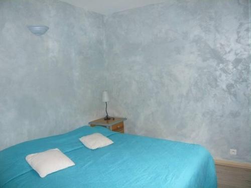 - un lit bleu avec 2 oreillers blancs dans une chambre dans l'établissement Maison dans les bois, à Sardan