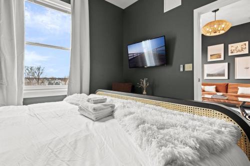 a bedroom with a white bed and a tv on a wall at King Bed An Alluringly Cozy Suite Xcape in Alexandria