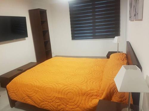 een slaapkamer met een geel bed en een televisie bij DEPARTAMENTO DE LUJO FULL AMOBLADO, A 3 MINUTOS DE AEROPUERTO in Guayaquil