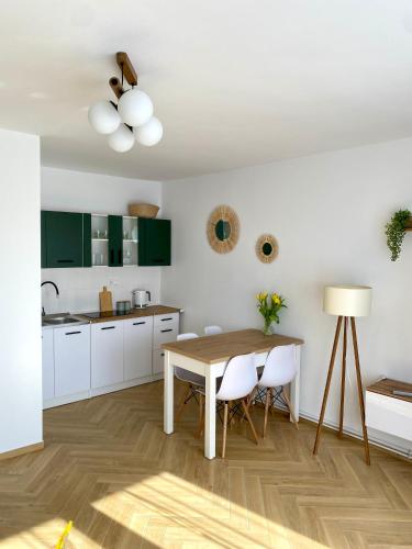 een keuken met witte kasten en een houten tafel bij Apartament Zielone Serce Miasta in Mrągowo