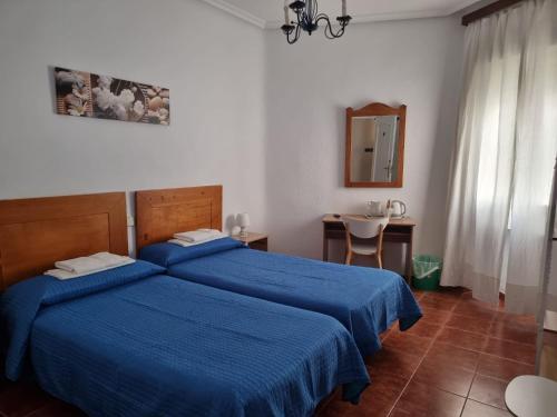 1 Schlafzimmer mit 2 Betten, einem Tisch und einem Spiegel in der Unterkunft Casa de Huéspedes Cuenca in Madrid