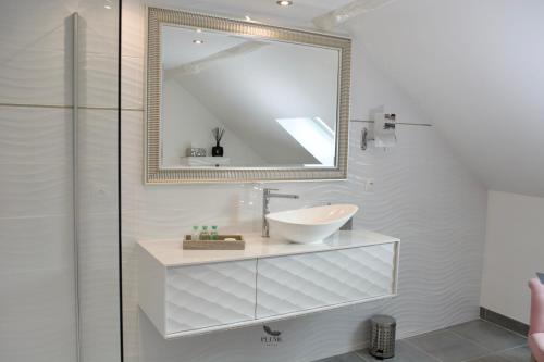 Baño blanco con lavabo y espejo en Plume Suites, en Fleurey-sur-Ouche