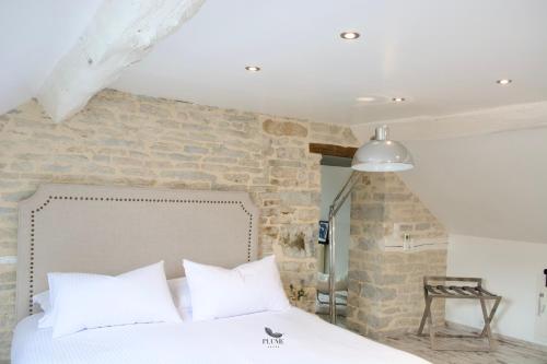 1 dormitorio con cama blanca y pared de ladrillo en Plume Suites, en Fleurey-sur-Ouche