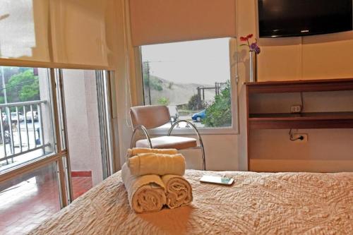 1 dormitorio con 1 cama con toallas y silla en Altair Hotel en San Clemente del Tuyú