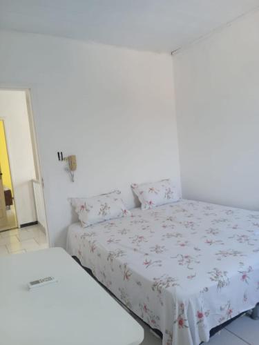 Bett in einem Zimmer mit einer weißen Wand in der Unterkunft Pousada Bahamas in Neópolis