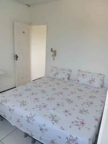 1 Schlafzimmer mit einem Bett mit Blumenbettdecke in der Unterkunft Pousada Bahamas in Neópolis